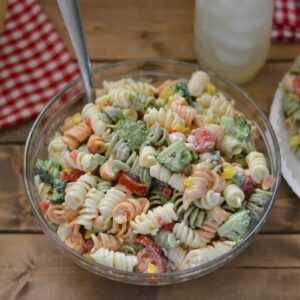 Glass bowl filled with broccoli and tomato pasta salad.