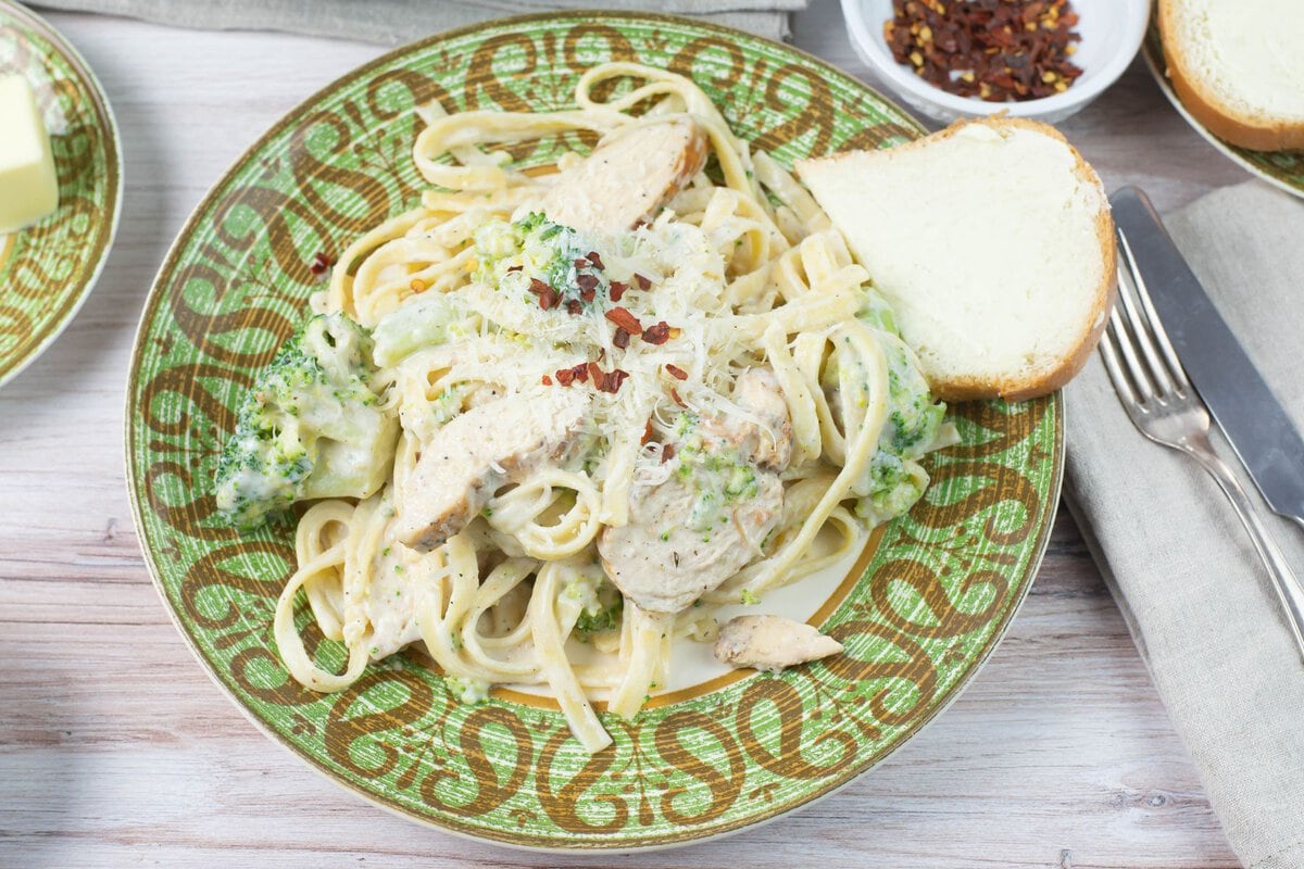 Serving Cajun chicken broccoli alfredo on a dinner plate.